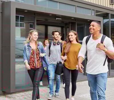Group of male and female students leaving higher education college.